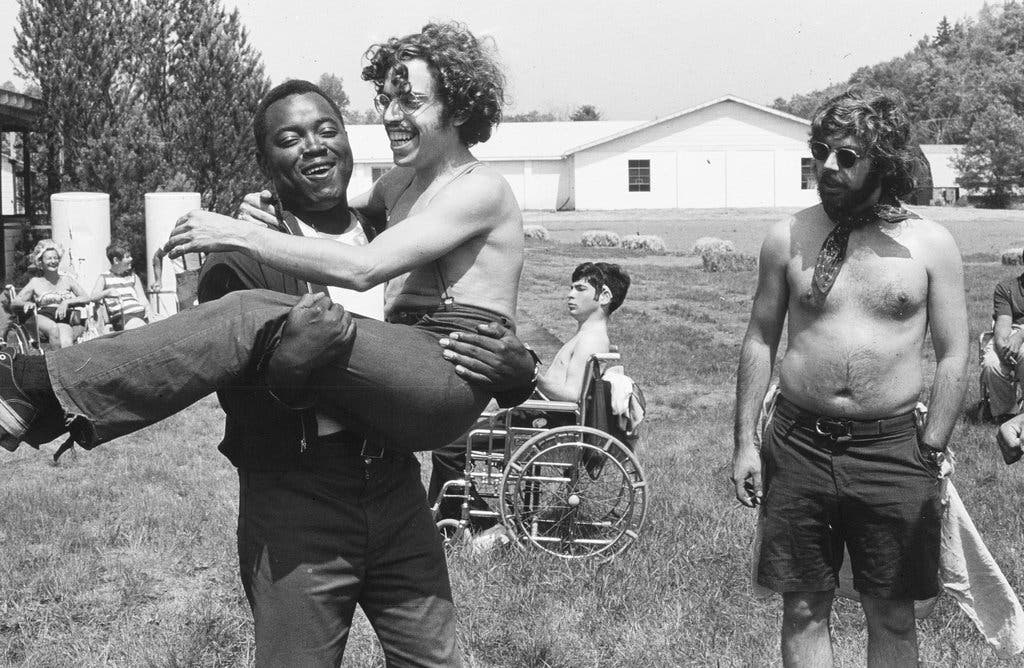 A black-and-white still from the film showing four people with different disabilities.